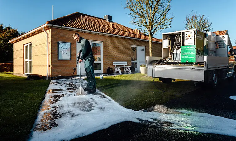 Sparvath bekæmper ukrudt med kogende vand i en fliseopgang til et hus